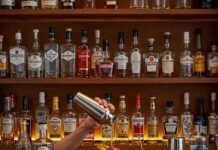 How to Stock a Home Bar: Essentials for Every Budget A Cozy Home Bar Scene with Someone Making a Cocktail.