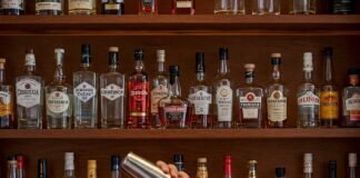 How to Stock a Home Bar: Essentials for Every Budget A Cozy Home Bar Scene with Someone Making a Cocktail.